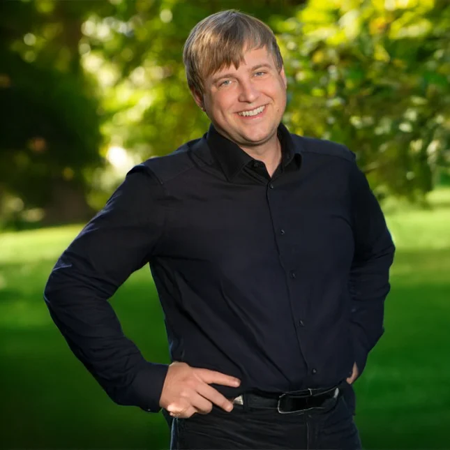 Sebastian Hilmer Landschaftsarchitekt bei Stockreiter GmbH. Zu sehen ist ein junger, lächelnder Mann in einem schwarzen Oberteil.