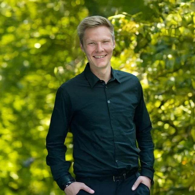 Thomas Erben Management im Landschaftsbau bei Stockreiter GmbH. Zu sehen ist ein junger, lächelnder Mann in einem schwarzen Oberteil.
