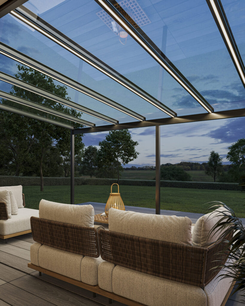 Moderne Terrasse mit Glasdach, zwei geflochtene Sofas, Tisch mit Laterne, blauer Himmel im Hintergrund.