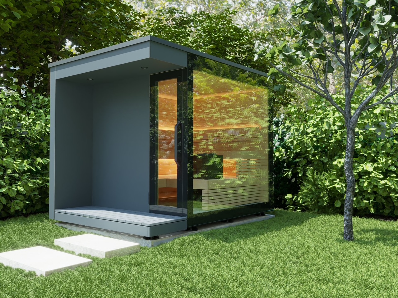Moderne, graue Gartenhütte mit Glasfront in einem grünen, bewaldeten Garten mit dichtem Laubbaum.