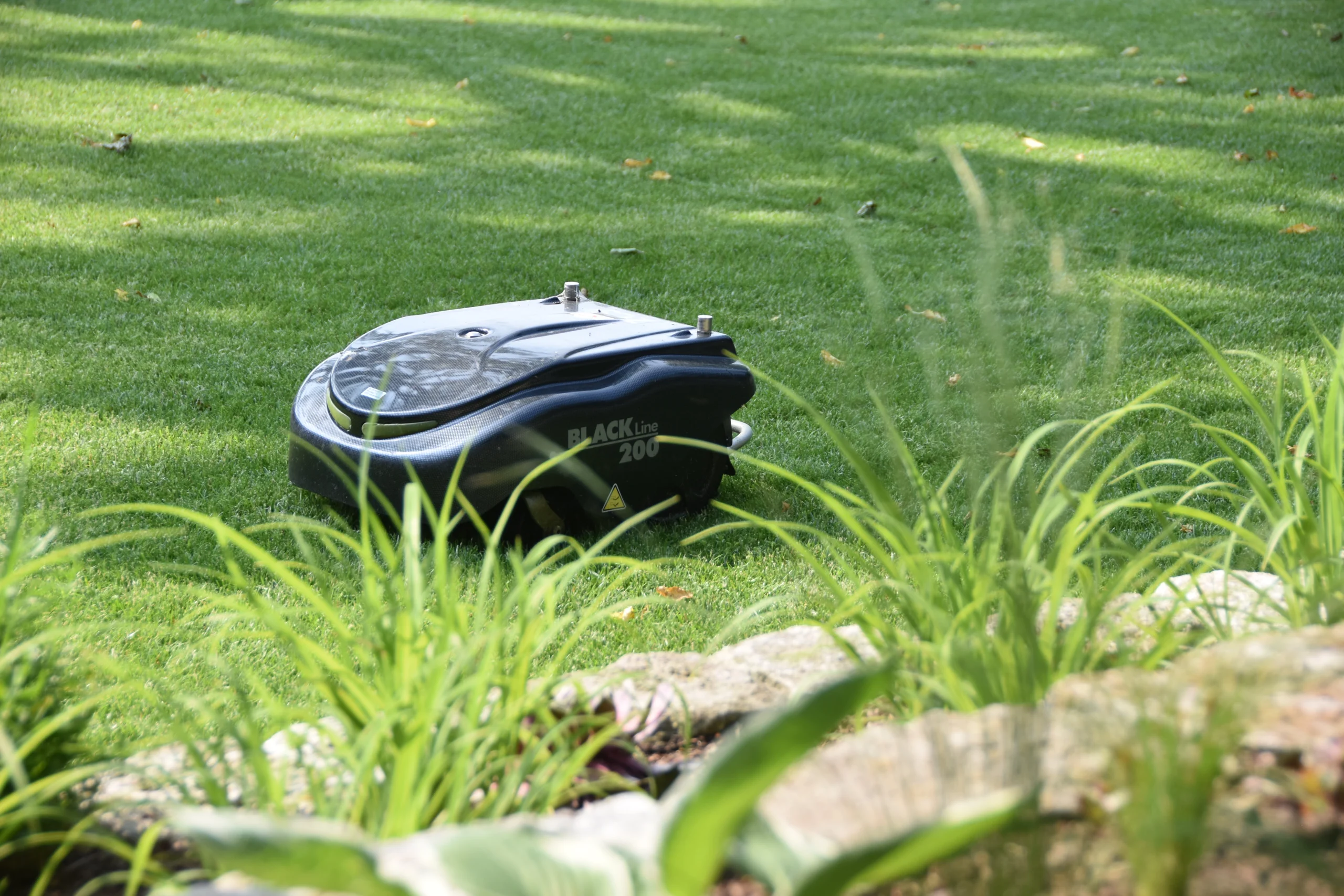 Ein moderner Rasenroboter pflegt einen grünen, gut geschnittenen Rasen in einem sonnigen Garten.