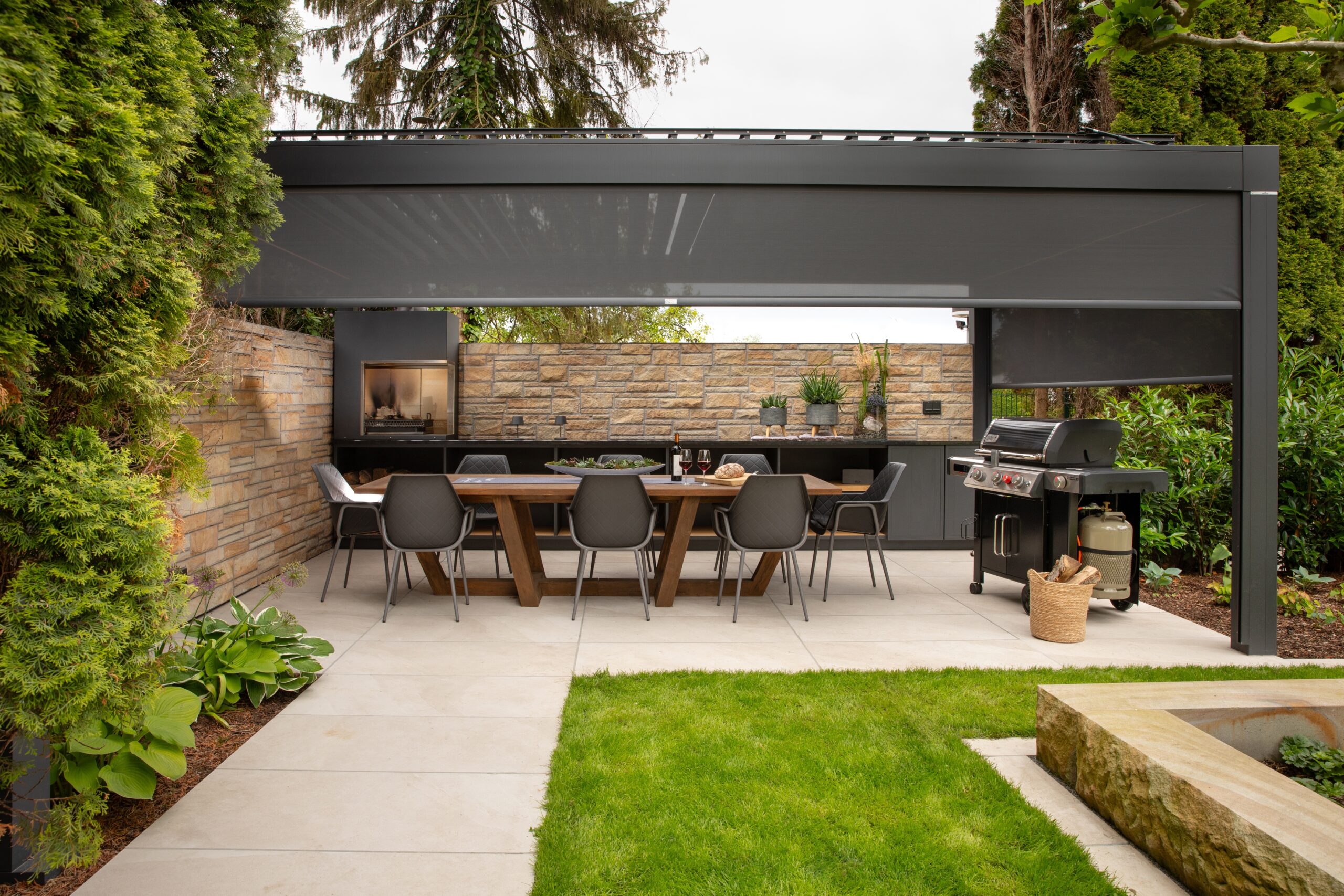 Moderner Essbereich im Freien mit Holztisch, Pergola, Grill und dekorativen Pflanzen.