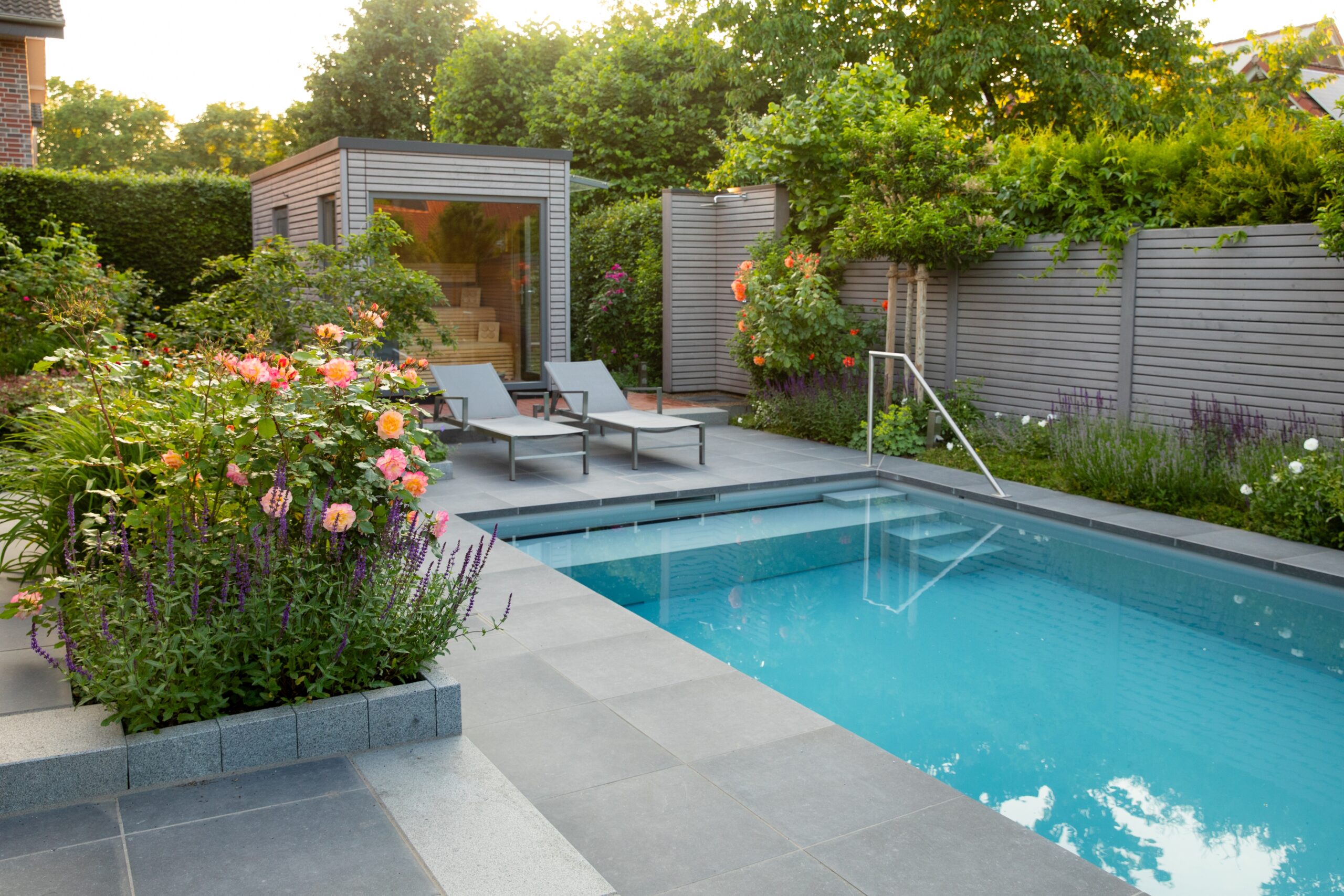 Moderner Garten mit Swimmingpool, Liegestühlen, Gartenhaus und üppigen Pflanzen; friedliche Atmosphäre.
