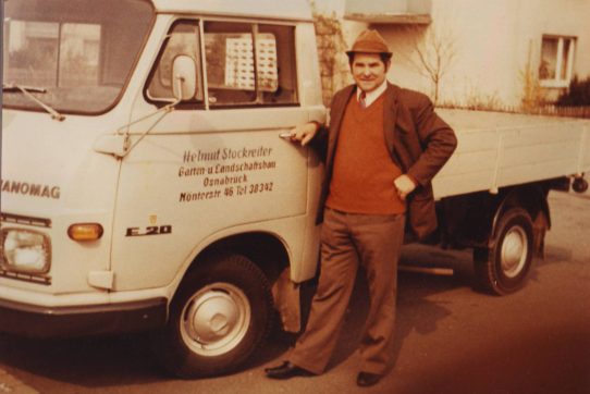 Ein Mann im Anzug lehnt lässig an einem Hanomag F20 Lastwagen, wirkt zufrieden und selbstbewusst.
