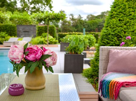 Ein entspannter Gartensitzbereich mit Pfingstrosen, einem gemütlichen Sofa und einem beruhigenden Pool.