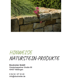 Natursteinmauer mit rosa blühender Pflanze, umgeben von Gras; beruhigende, natürliche Ästhetik.